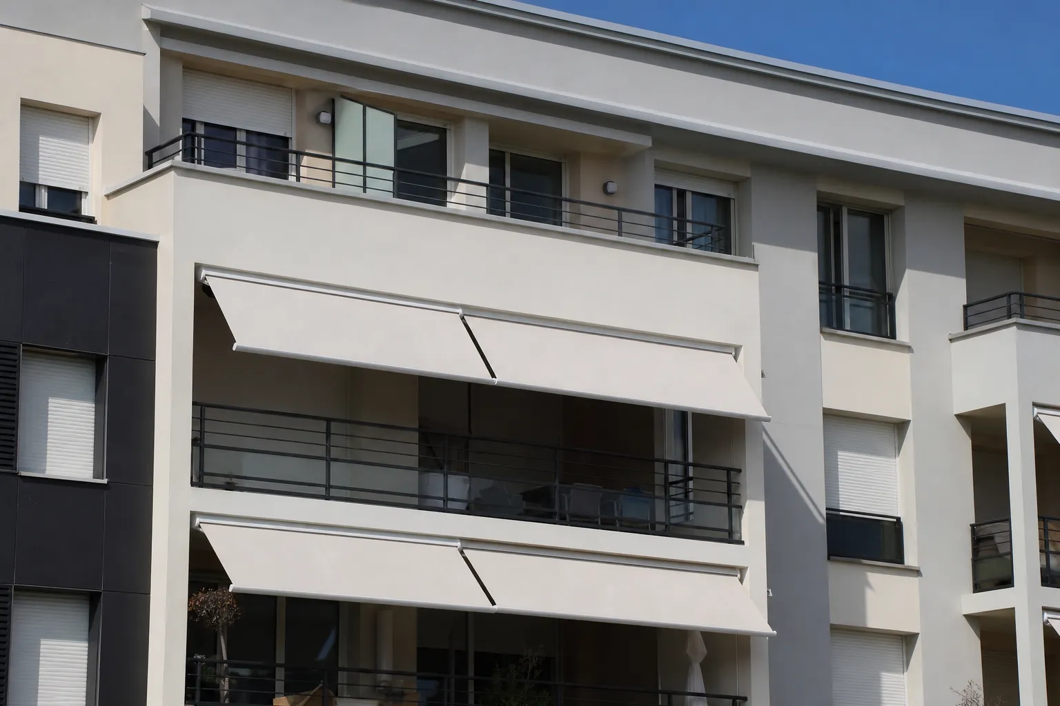 Façade d’immeuble avec plusieurs balcons équipés de stores bannes et volets roulants assortis