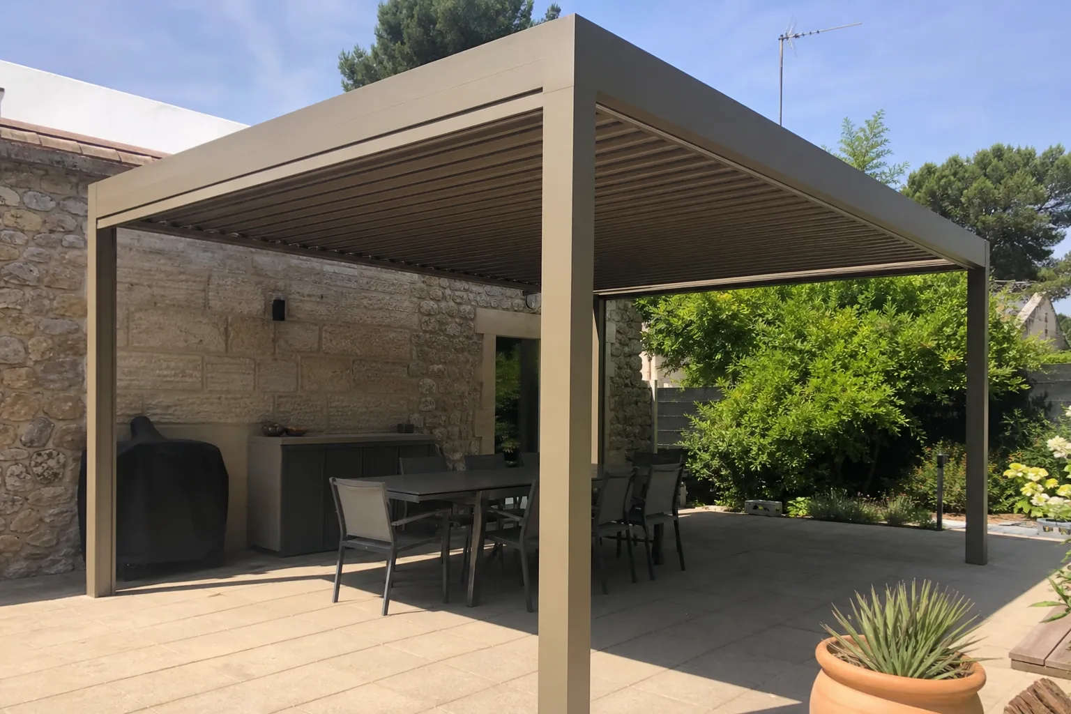 Pergola bioclimatique aluminium ton bronze, lames orientables fermées, terrasse à l’ombre