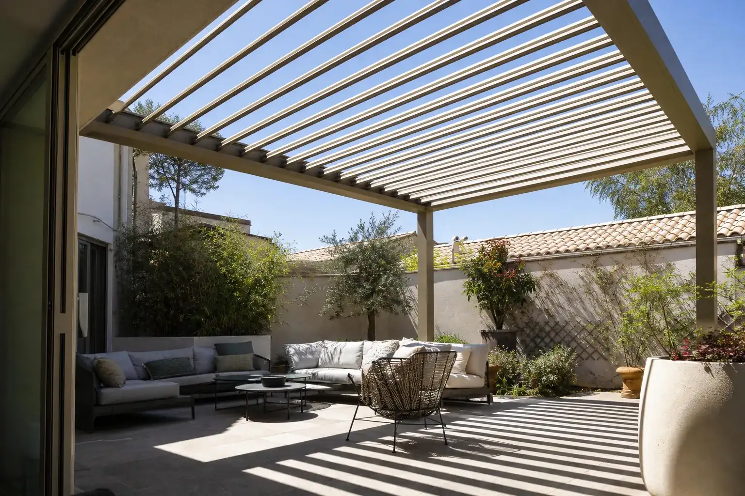 La même pergola bioclimatique, lames orientables ouvertes, ciel dégagé et plein soleil filtré