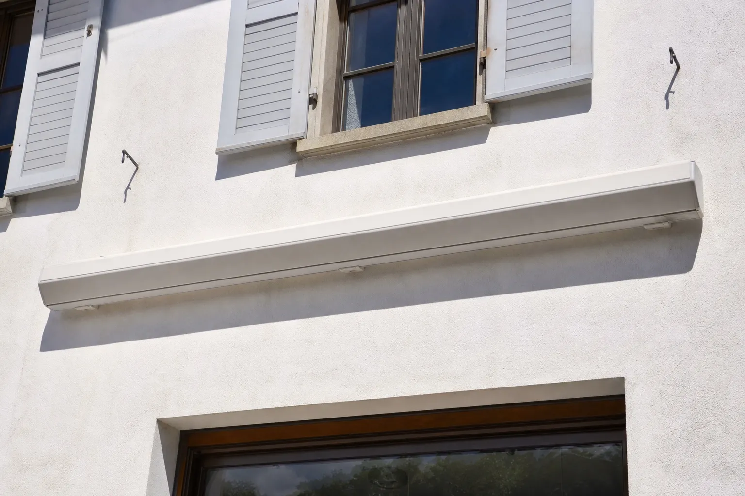 Store banne à armature aluminium entièrement rétracté dans son coffre, façade claire