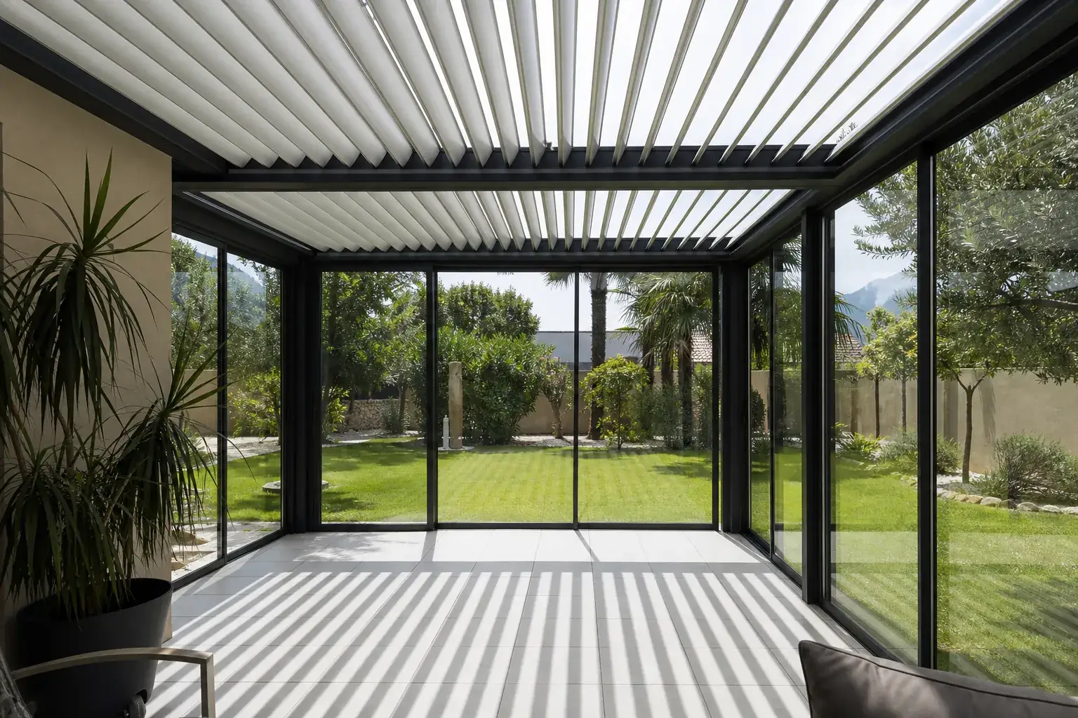 Brise-soleil orientable au-dessus d’une véranda vitrée, lames fermées projetant une ombre nette