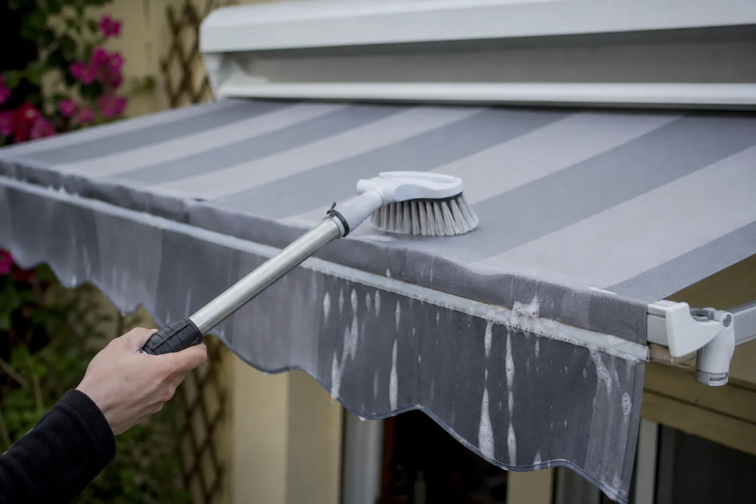 Nettoyage à la brosse douce d’un store banne à toile déployée