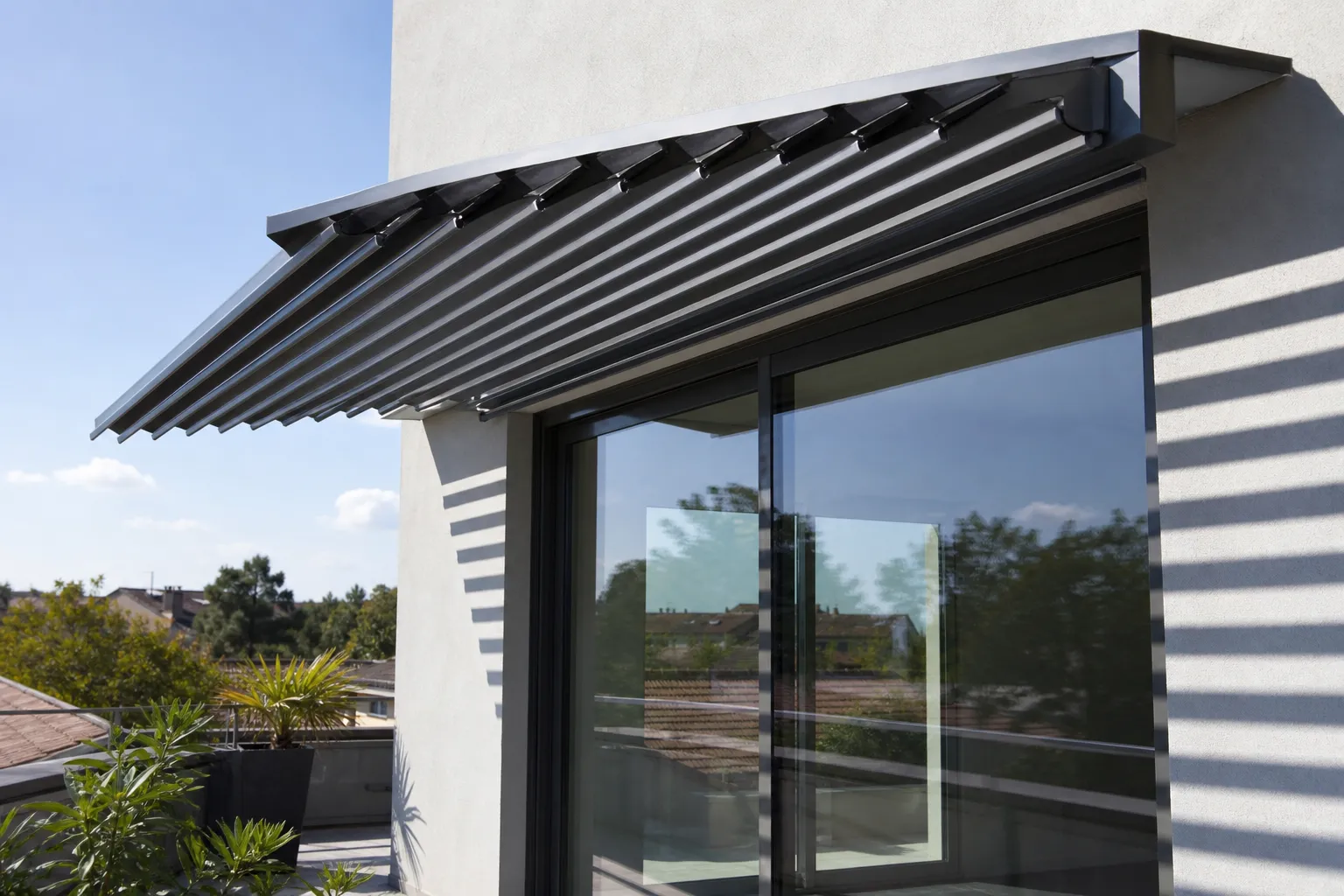 Brise-soleil orientable en lames aluminium au-dessus d’une baie vitrée de terrasse